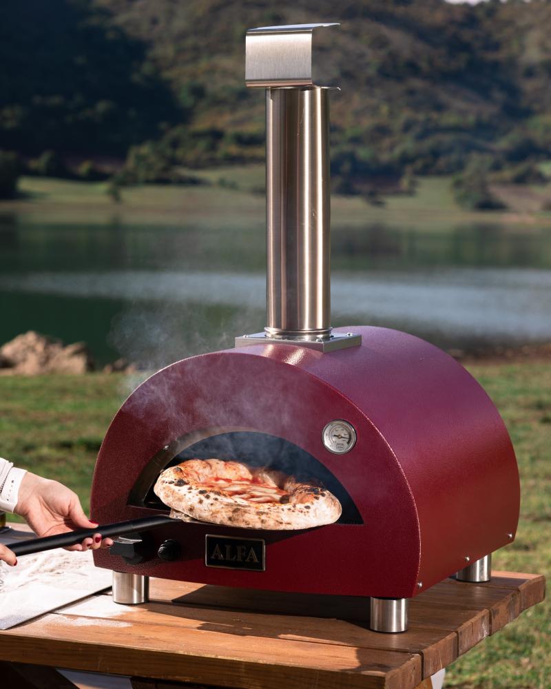 Homemade pizza is being cooked using an Alfa Forni gas pizza oven at high heat.