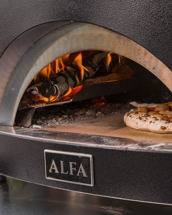 Wood-burning oven with a pizza baking using Alfa Forni pizza oven.