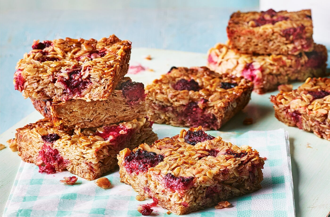 Oat and raspberry flapjacks stacked on a plate, a simple treat often featured in easy baking recipes for toddlers.