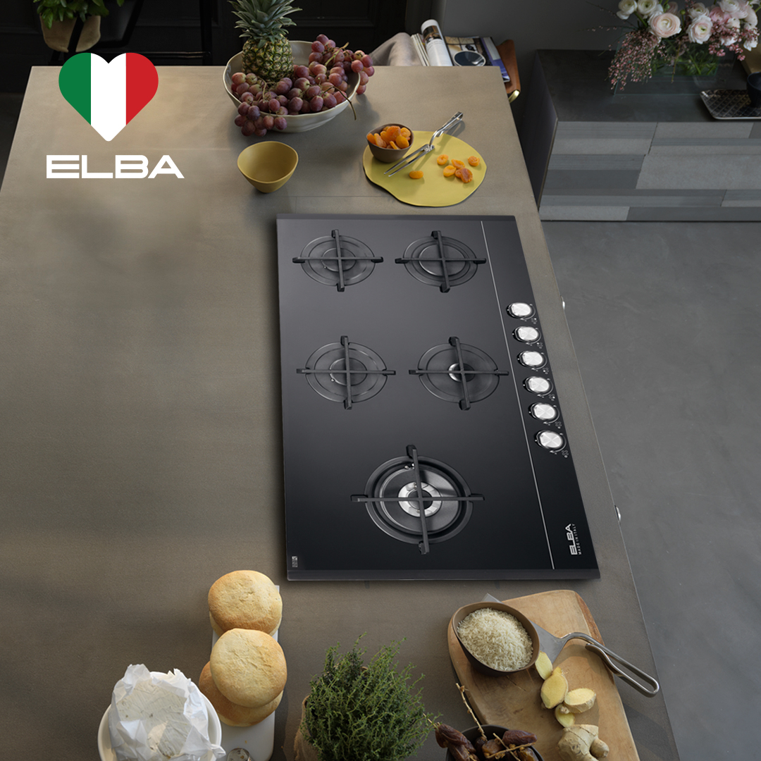 Modern kitchen with sleek black ELBA cooking hob, four burners, surrounded by fresh produce like grapes, apricots, and bread, creating a stylish and inviting atmosphere.