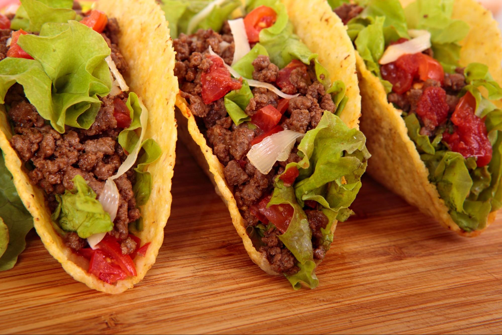 Crispy beef tacos filled with seasoned meat, topped with fresh salsa, lettuce, and shredded cheese.