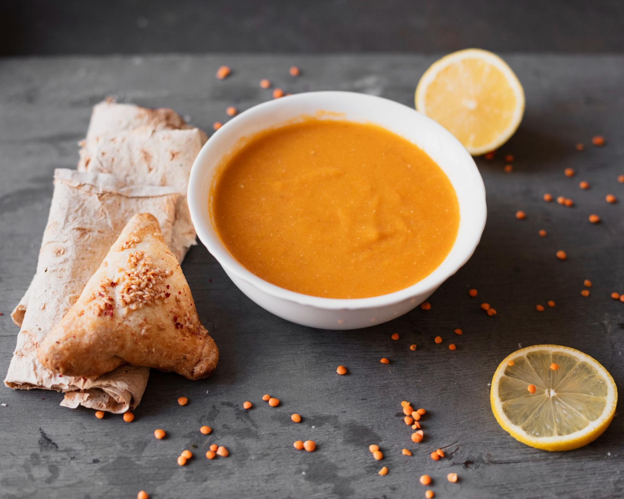 A warm bowl of lentil soup served with khubz bread on the side, perfect for dipping and hearty meals.